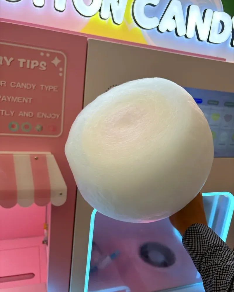 A giant cotton candy flower held up in front of the cotton candy machine