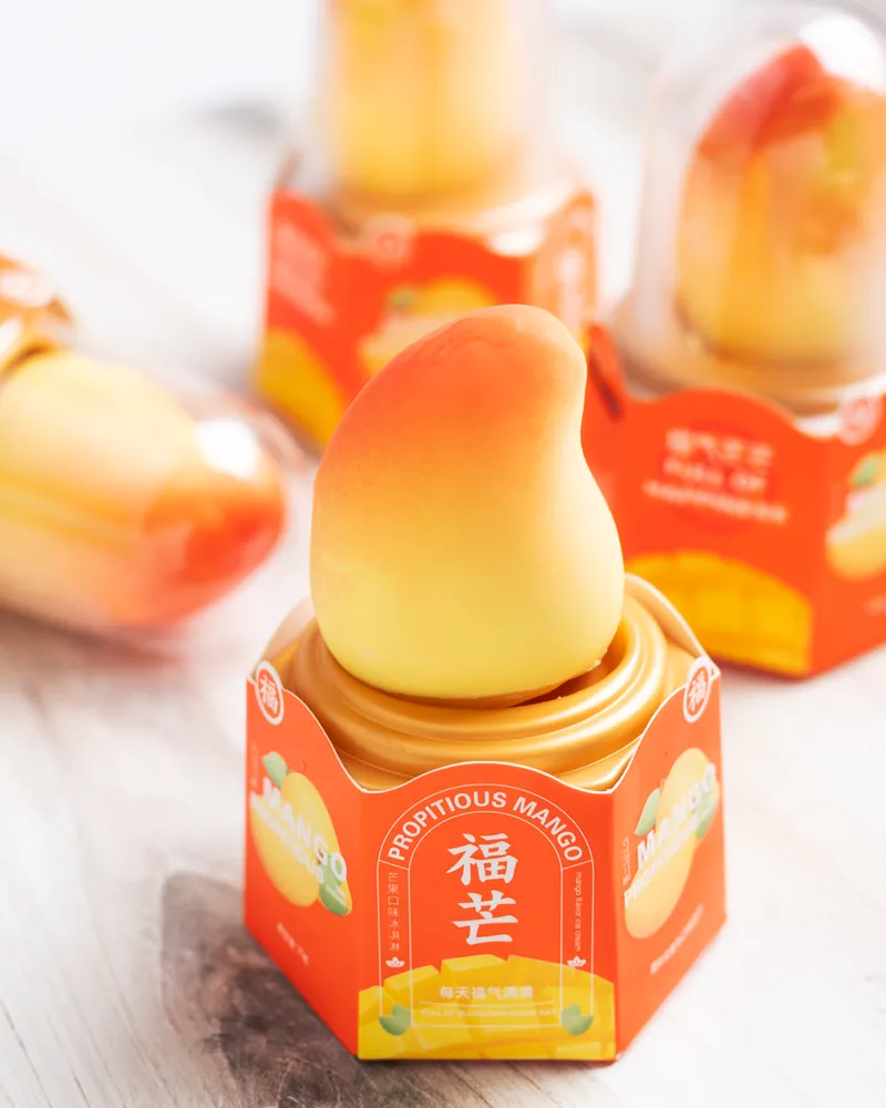 A mango-shaped ice cream on its Propitious Mango base, with more domed mangoes behind it