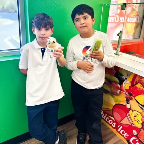 Two boys holding a cone and a paleta